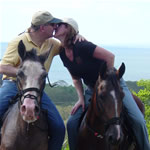 Honeymooners kissing on horseback