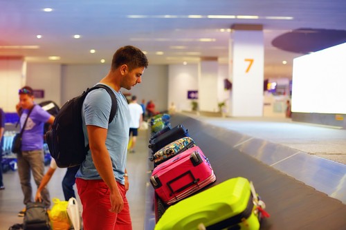 man in airport luggage and Costa Rica customs area before starting family adventure vacation