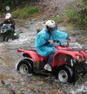 two teenagers drive atvs across a river on personalized family vacation in costa rica