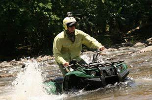 a man drives an atv across a river on a private adventure across costa rica