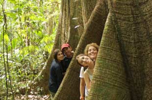 Mom, dad, and two daughters posing in tree roots in Costa Rica rain forest