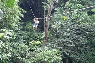 distant view of person ziplining over the canopy in costa rica