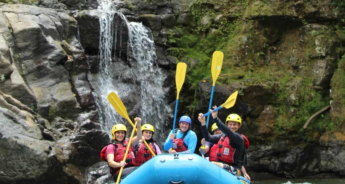 Group whitewater rafting next to a waterfall