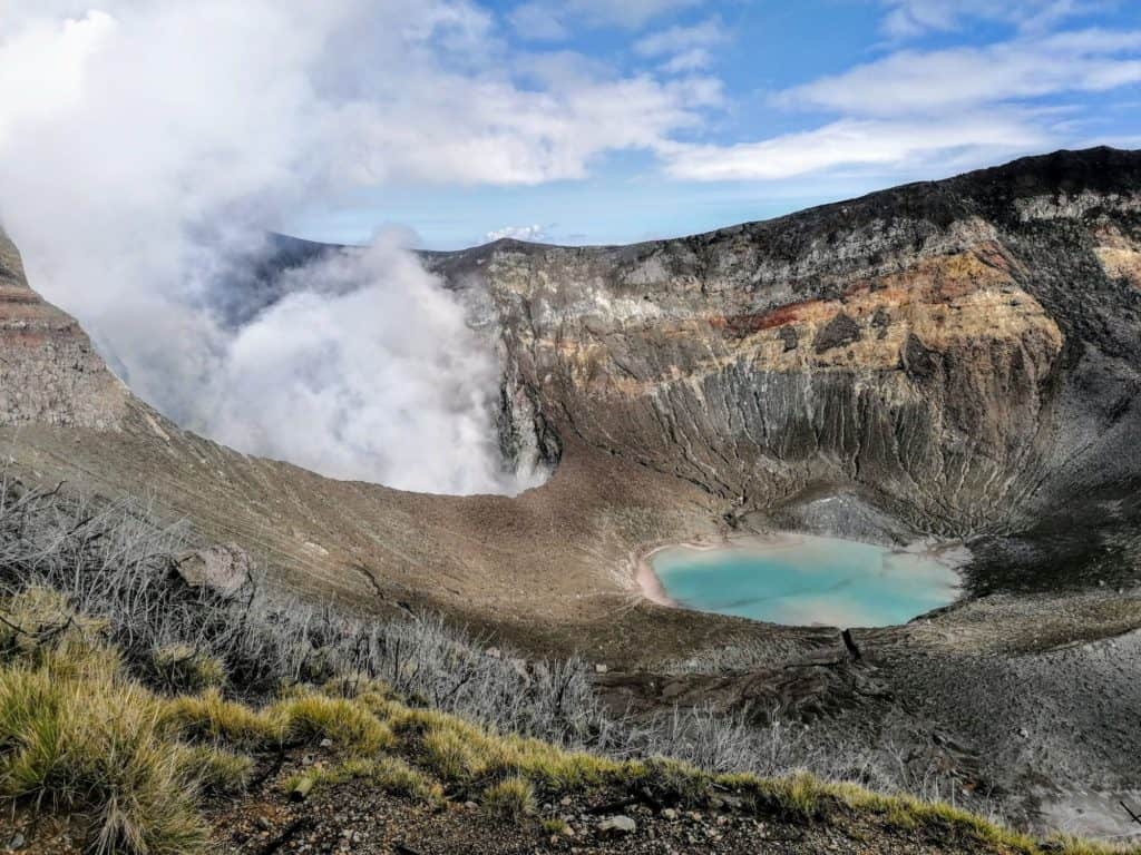 View of the Turrialba volcano crater with blue lake and smoking fumeroles