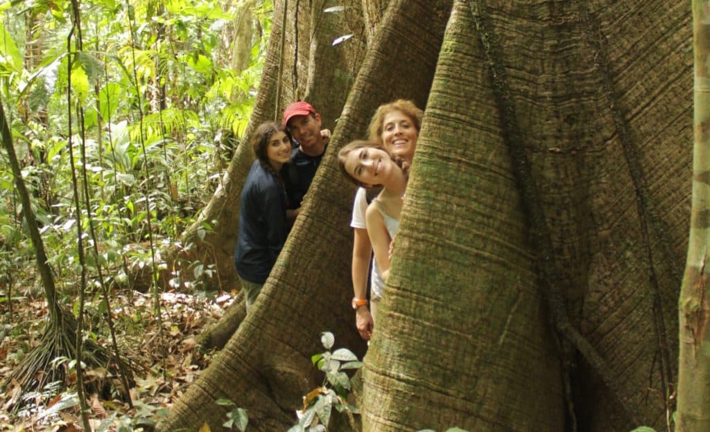 A family standing at the base of a giant tree in Costa Rica