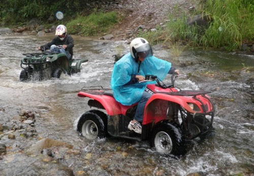 two teenagers drive atvs across a river on personalized family vacation in costa rica