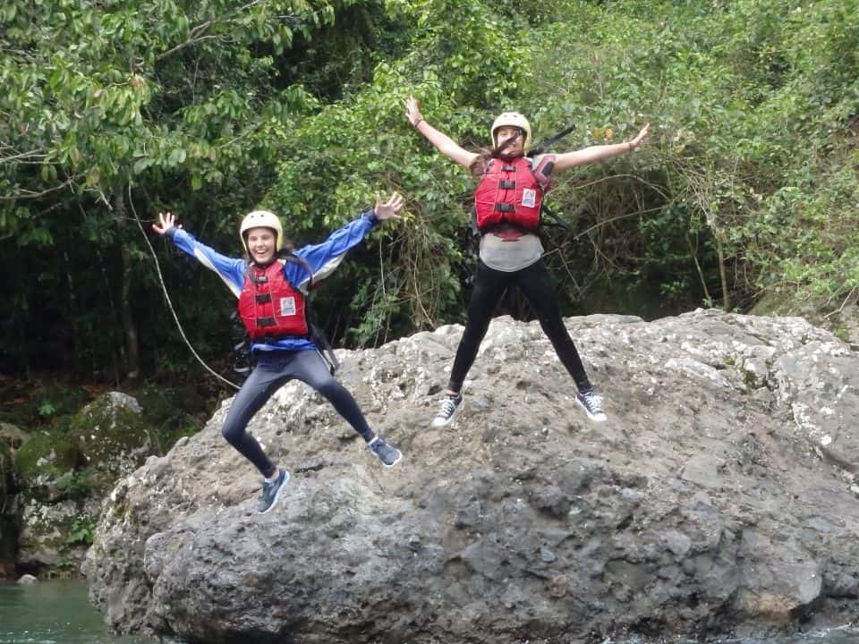 Rock jumping two happy people jump from a rock into the river on a personalized family vacation in costa rica