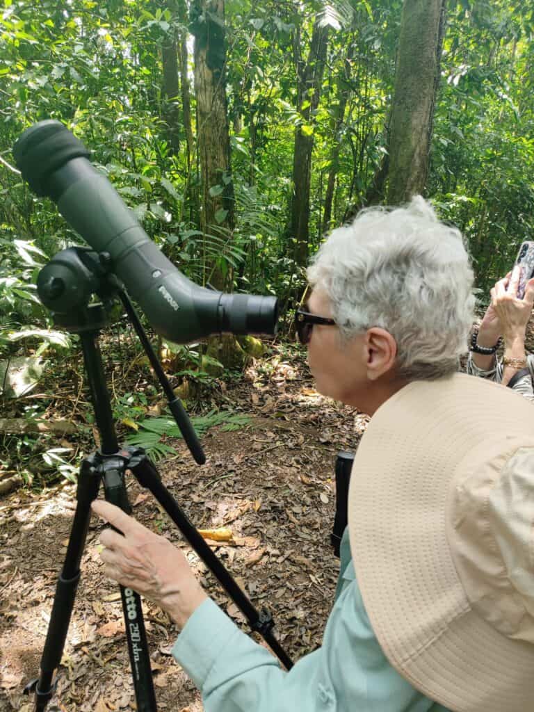 A senior woman looking through a spotting scope on a tour at La Selva Biological Station in Sarapiqui, Costa Rica