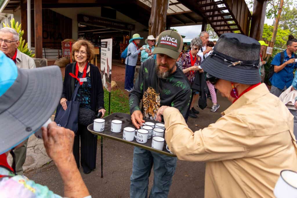 A Hacienda Doka guide offering coffee cups on a tray