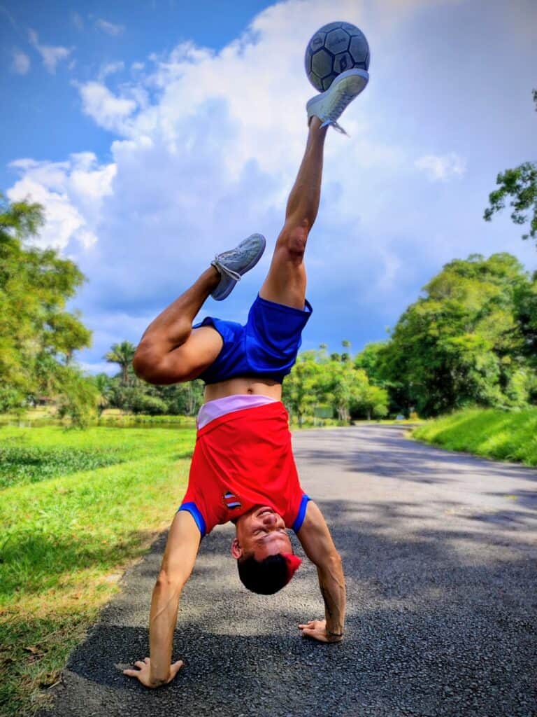 Dayronman performing an upside down trick with a football balanced on his foot